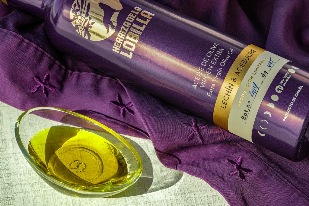 La Guía Definitiva para Identificar un Buen AOVE: 8 Claves Esenciales que No Fallan 3 Botella de aceite de oliva virgen extra variedad lechín y acebuche tumbada, mostrando el código único de edición limitada y una muestra del producto sobre un recipiente de cristal