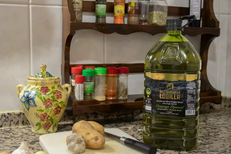 Garrafa de aceite oliva virgen extra Coupage Especial con fondo de cocina, tabla de cortar y especias